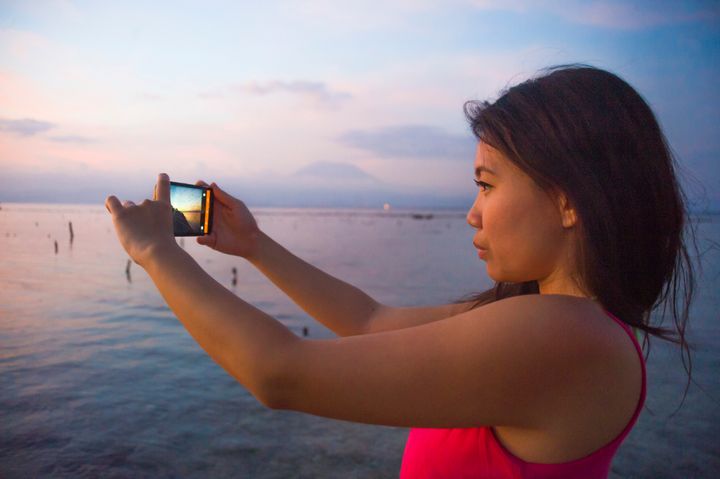 Een jonge vrouw maakt een foto tijdens zonsondergang op Bali. Foto: Shutterstock.com